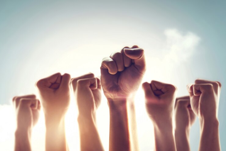 Folla di manifestanti. La gente alzò il pugno in aria combattendo per i propri diritti con effetto luce solare. Concetto di rivoluzione o protesta.