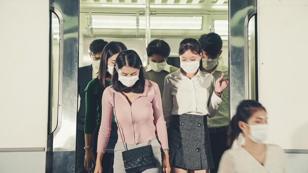 Folla di persone che indossano la maschera facciale durante un viaggio in treno pubblico affollato della metropolitana. Malattia di coronavirus o focolaio pandemico COVID 19 e problema di stile di vita urbano nel concetto di ora di punta.