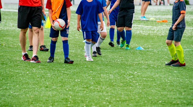 Folla molti bambini che giocano a calcio sul campo in erba degli stadi