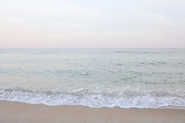 Fondo astratto dell'estratto di bella estate del mare. Spiaggia di sabbia dorata con oceano blu e cloudscape e tramonto nella parte posteriore.