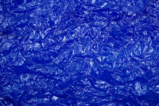 Fondo astratto di struttura della carta di plastica trasparente blu brillante di cellophane sgualcito