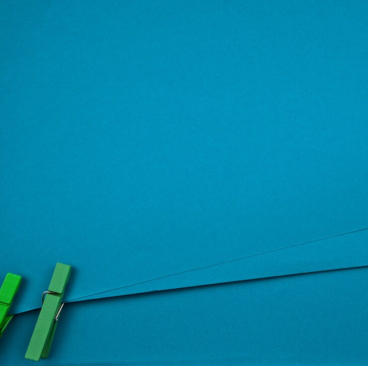 Fondo blu della carta in bianco. Rilegatura con mollette artigianali in legno verde. Design minimale.