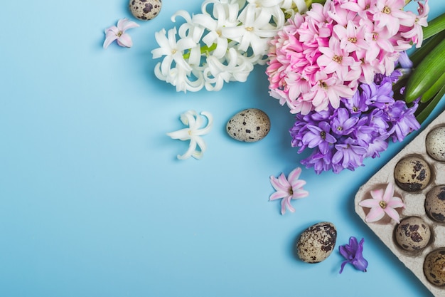 Fondo blu di festa di Pasqua. Uova di quaglia e fiori di giacinto