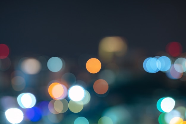 Fondo defocused del bokeh urbano astratto della luce notturna con area di spazio del cielo