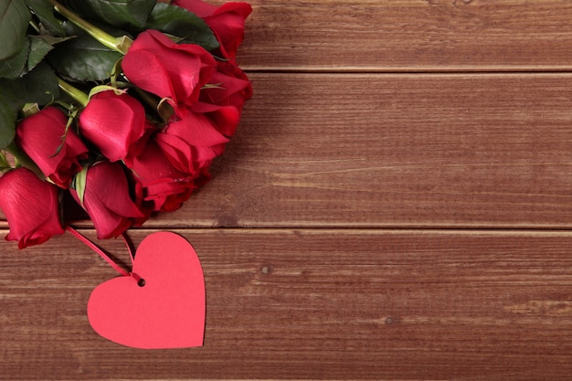 Fondo del biglietto di S. Valentino dell&#39;etichetta del regalo e rose rosse su legno