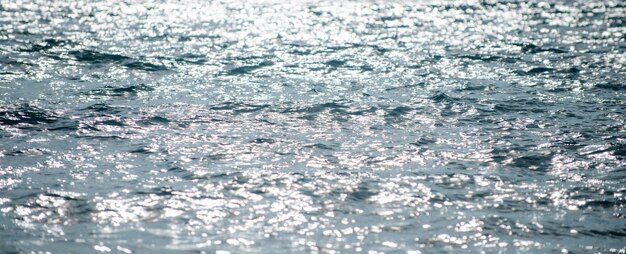 Fondo del mare di estate. Texture della superficie dell'acqua. Brillante motivo a ondulazione dell'acqua blu.