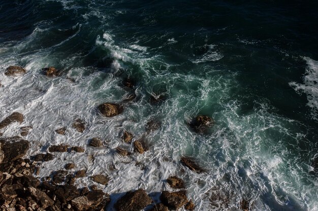 Fondo dell'onda dell'oceano che rompe la costa rocciosa dell'acqua di mare