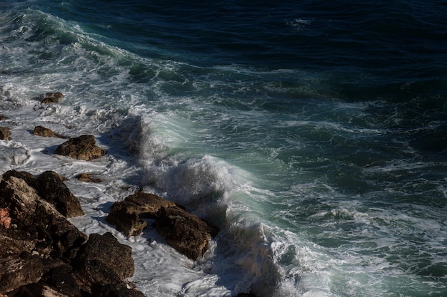 Fondo dell'onda dell'oceano che rompe la costa rocciosa dell'acqua di mare