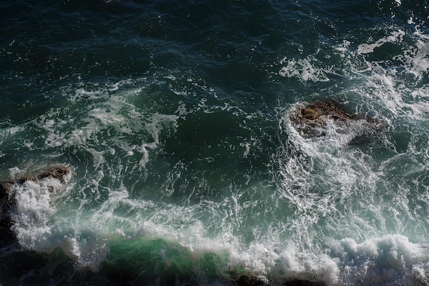 Fondo dell'onda dell'oceano che rompe la costa rocciosa dell'acqua di mare