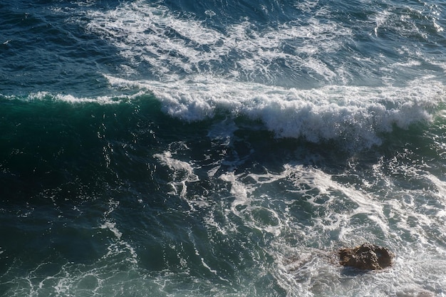 Fondo dell'onda dell'oceano che rompe la costa rocciosa dell'acqua di mare