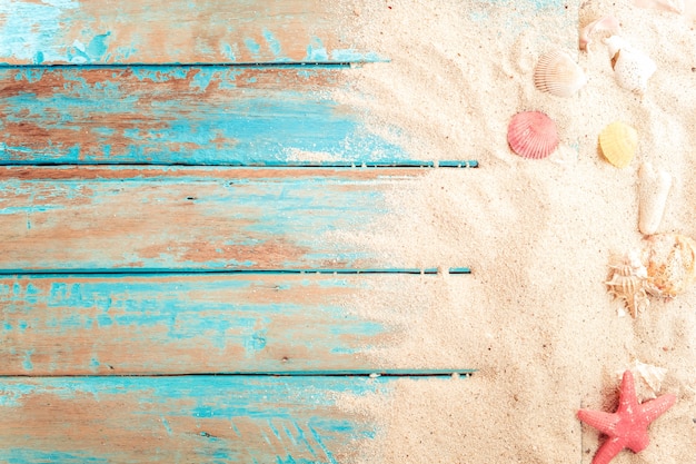 Fondo della spiaggia - sabbia della spiaggia con le coperture, stella marina sulla plancia di legno in mare blu