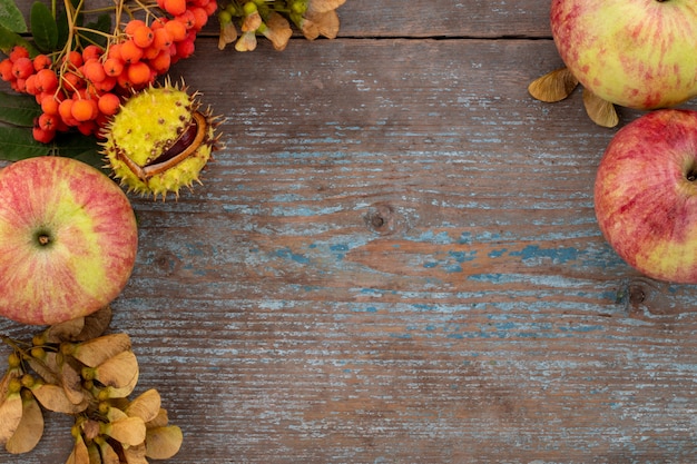 Fondo di autunno dalle foglie e dai frutti caduti con la regolazione di posto d'annata sulla vecchia tavola di legno. Concetto di giorno del ringraziamento