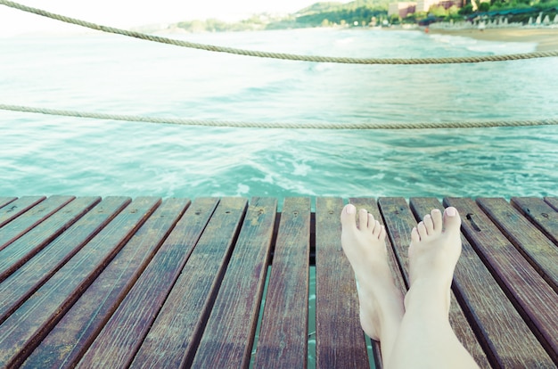 Fondo di concetto di vacanze estive con le gambe sopra le plance di legno