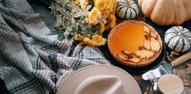 Fondo di cottura autunnale con foglie autunnali gialle di zucca di torta di zucca su fondo di legno