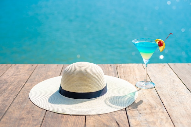 Fondo di estate, cappello bianco ed estate che bevono sulla spiaggia