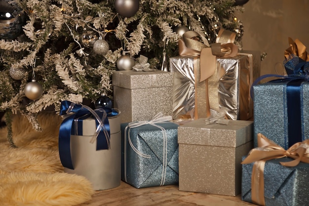 Fondo di festa di Natale delle scatole con i regali del nuovo anno sotto l'albero di Natale decorato. Regali di bellezza Imballato con nastri. Decor sotto l'albero nell'interiore domestico. Avvicinamento. Copia spazio