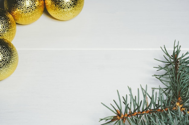 Fondo di legno bianco di Natale con le campane dei coni delle palle dorate del ramo del pino Spazio della copia