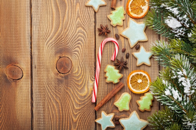 Fondo di legno di natale con i biscotti del pan di zenzero delle spezie dell'albero di abete della neve