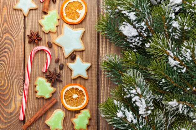 Fondo di legno di Natale con l'albero di abete della neve e i biscotti di pan di zenzero