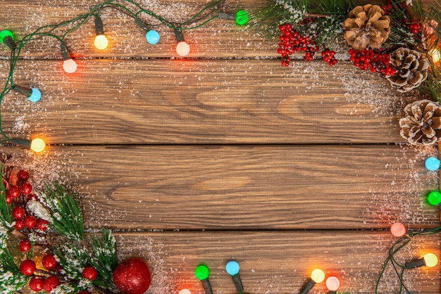 Fondo di legno di Natale con la ghirlanda luminosa. Ghirlanda luminosa intorno a tavole di legno decorate