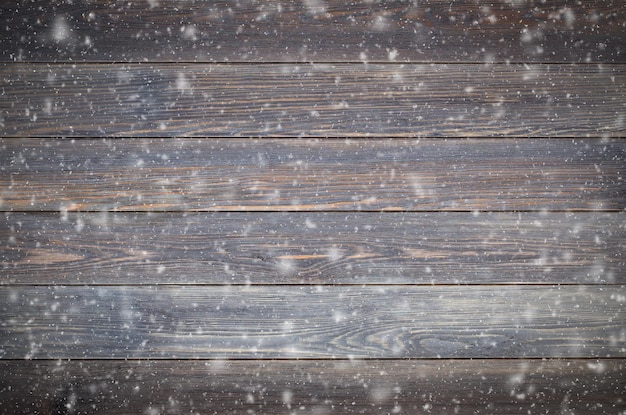 Fondo di legno marrone fatto di tavole con fiocchi di neve. Il concetto dell'umore invernale.