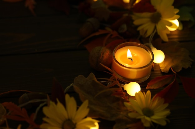 fondo di legno rustico scuro con candele, foglie di autunno e spazio della copia