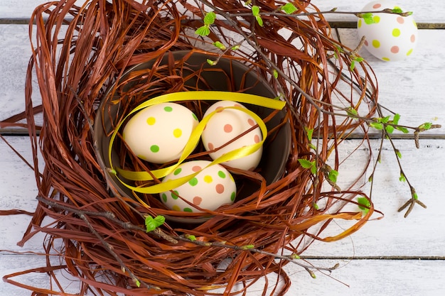 Fondo di Pasqua con le uova colorate nel nido e nei bordi bianchi