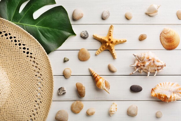 Fondo di vacanza su legno bianco, vista superiore con lo spazio della copia. Cappello di paglia e conchiglie