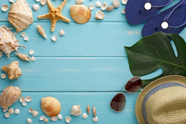 Fondo di vacanza su legno blu, vista superiore con lo spazio della copia. Accessori da spiaggia, infradito e conchiglie