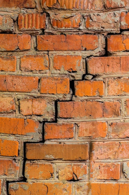 Fondo e struttura del primo piano del muro di mattoni arancioni incrinati profondi