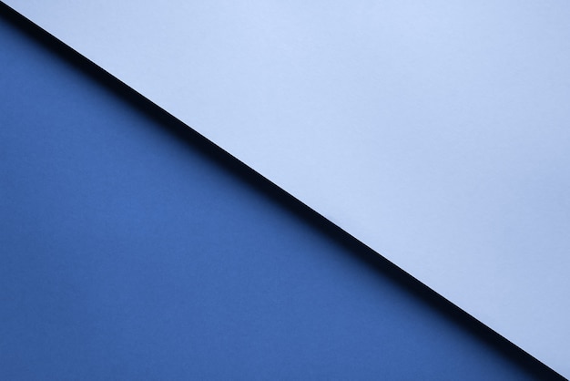 Fondo geometrico astratto di due pezzi di carta blu che si trovano uno sopra l'altro con un'ombra.