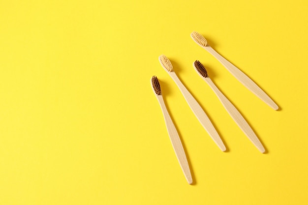 Fondo giallo di spazzolini da denti di bambù di legno naturale della famiglia. Senza plastica