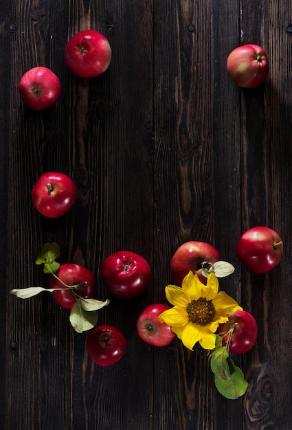 Fondo in legno con mele rosse e girasole. Disposizione piatta