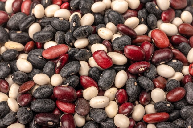 Fondo multicolore dei fagioli della miscela. Pila di fagioli in tre colori bianco, rosso, nero. cucchiaio paletta di legno con fagioli di tre colori