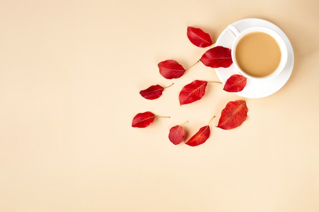 Fondo piatto autunnale su giallo. Composizione con foglie rosse realistiche e tazza di caffè. Ciao ottobre concept