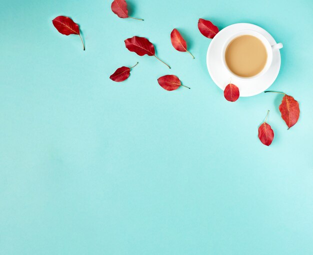 Fondo piatto autunnale sul blu. Composizione con foglie rosse realistiche e tazza di caffè. Ciao ottobre concetto. Copia spazio