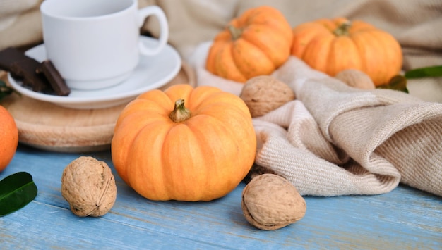 Fondo piatto autunnale. Zucche, mele, noci, foglie, tazze e maglione su fondo di legno.