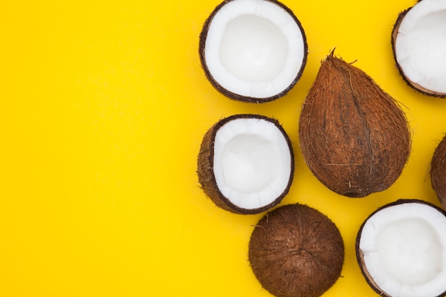 Fondo tropicale della noce di cocco di estate metà e noci di cocco intere su un fondo giallo