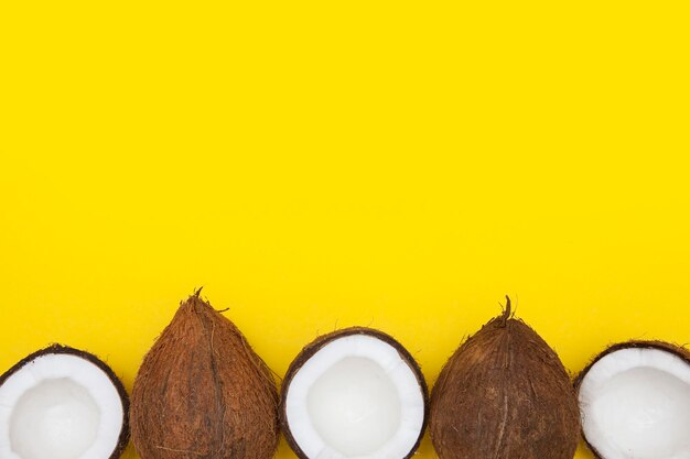 Fondo tropicale della noce di cocco di estate metà e noci di cocco intere su un fondo giallo