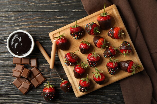 Fonduta di cioccolato. Fragola in cioccolato su fondo di legno, vista superiore