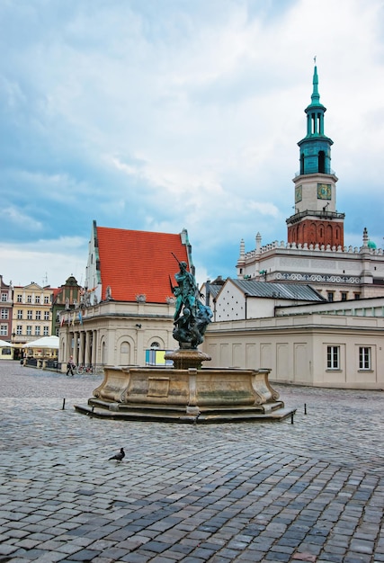 Fontana del Nettuno sulla Piazza del Mercato Vecchio nel centro della città di Poznan, Polonia. Guglia del Municipio della Città Vecchia e persone sullo sfondo