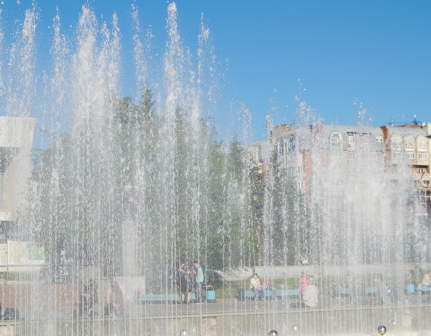 Fontana della città con getti d'acqua e persone a caso la vista attraverso lo spray