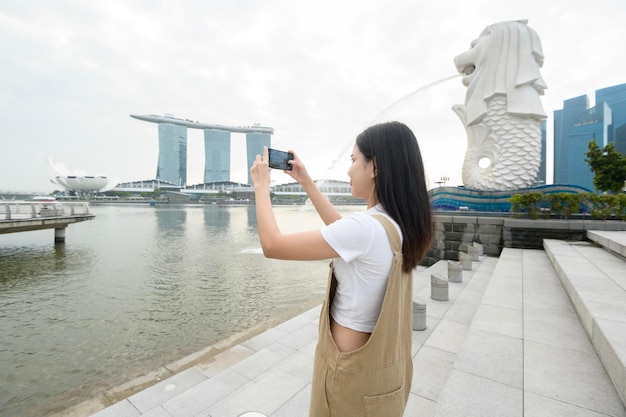 Fontana di Merlion di fronte alla baia di Marina con una giovane turista asiatica