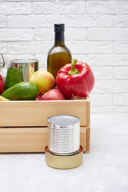 Food stocks in a wooden box. Vegetables, oil ,fruits, canned food, pasta. Donation, food delivery, coronavirus