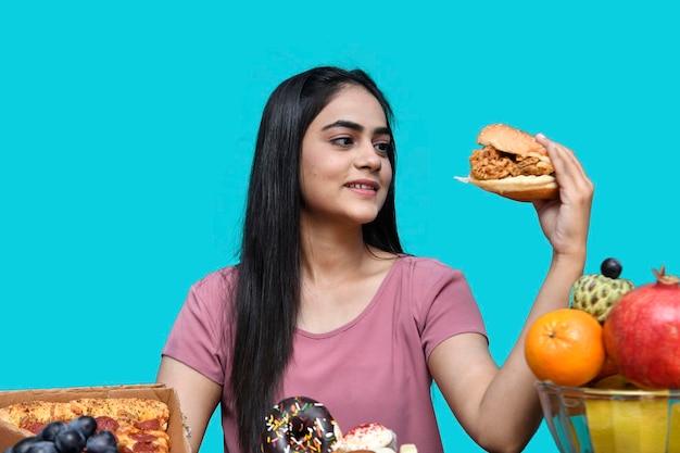 foodie ragazza seduta al tavolo della frutta con in mano hamburger modello pakistano indiano