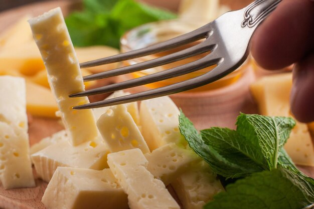 Forchetta che raccoglie un pezzo di formaggio primo piano Prodotti lattiero-caseari che mangiano cibo sano concetto di nutrizione organica naturale