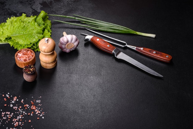 Forchetta coltello spezie ed erbe aromatiche tagliere su uno sfondo di cemento scuro