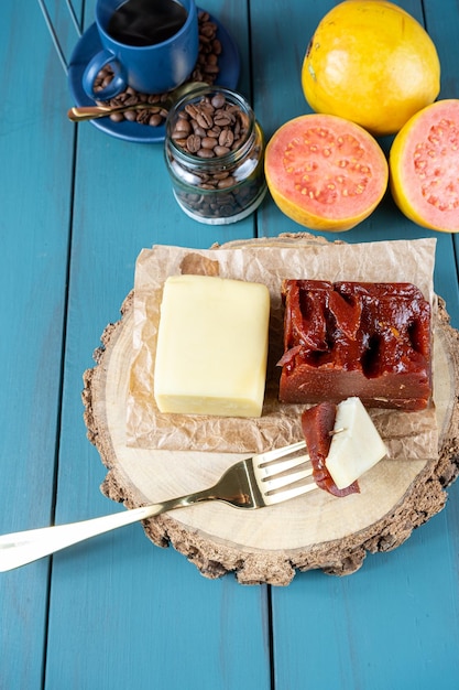 Forchetta con pezzi di guava dolce con formaggio su una tavola di legno accanto a fagioli e tazza di caffè verticale