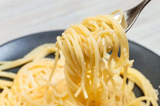 Forchetta con spaghetti da vicino su piatto nero