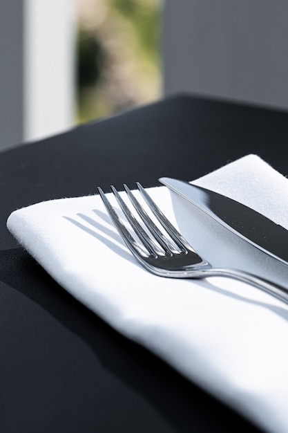 Forchetta e coltello con tovagliolo bianco sul tavolo in un ristorante di lusso all'aperto menu raffinato per matrimoni...